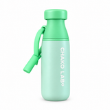 A Chako Lab insulated bottle with a mint green cap and upper body, a pale mint lower body, and a bright blue carrying loop attached to the side.