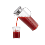 Clear glass pitcher pouring red juice into a clear glass 