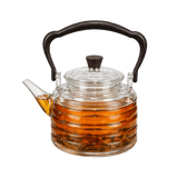 Clear glass teapot with black handle and lid knob. The image show the teapot filled with tea