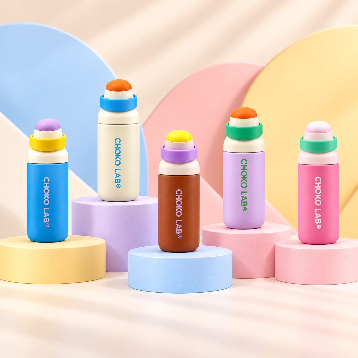 Five CHAKO LAB 750 ml bottles on pastel podiums including pink | زجاجات شكولاب بخمسة ألوان تشمل الوردي على خلفية ملونة
